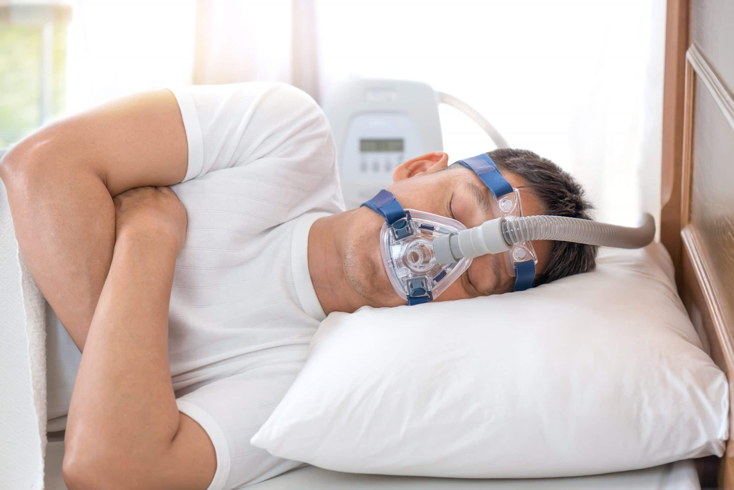 Homme dormant dans son lit et portant un masque CPAP, thérapie de l'apnée du sommeil
