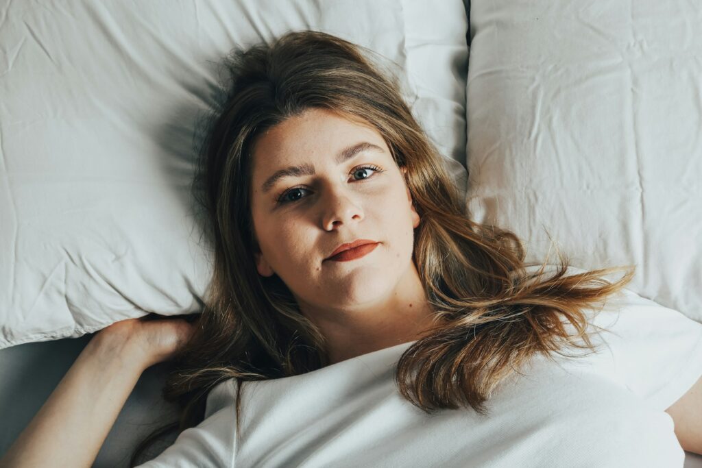 a woman laying on a bed with white sheets